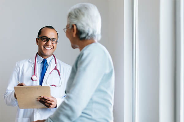 Male doctor checking senior female patient and smiling