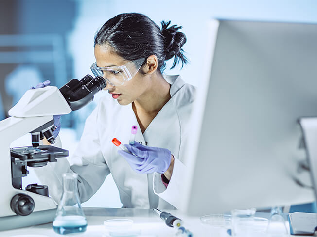 Female physician working in a lab looking in a microscope