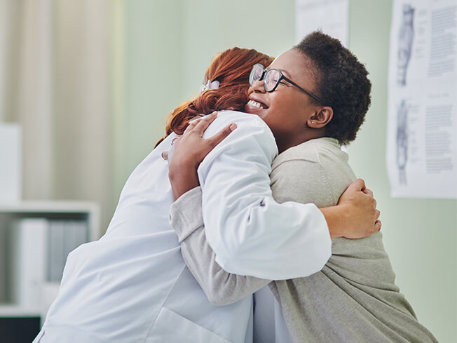 female physician hugging female patient for web