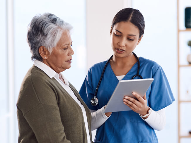 A female oncologist reviewing test results with an elderly female patient