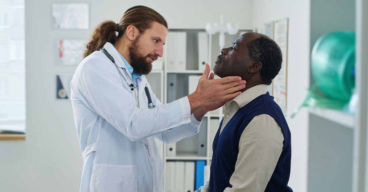 endocrinologist checking thyroid of mature male patient