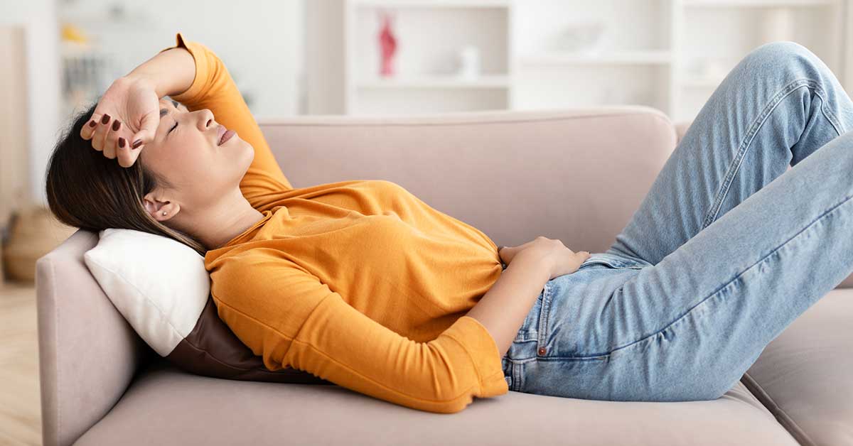 woman laying on couch feeling sick