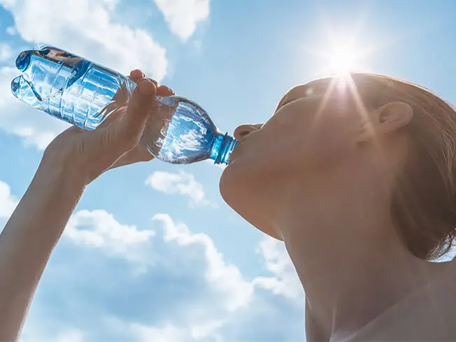 young woman drinking water to beat the heat