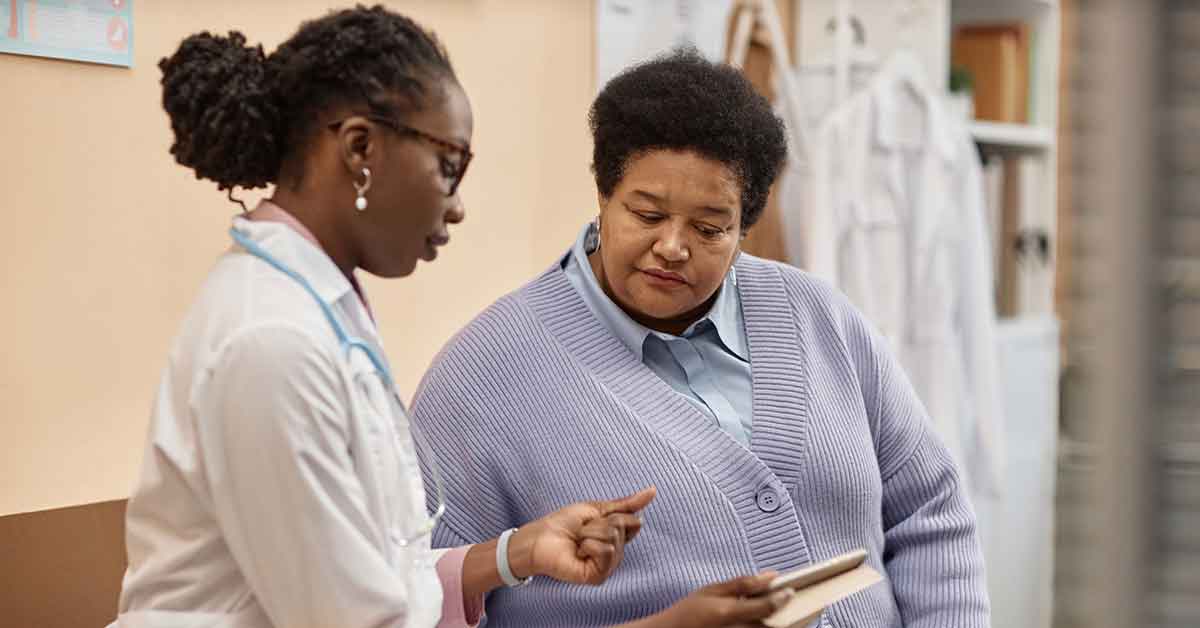 Female Patient Listening to Doctor Holding Table