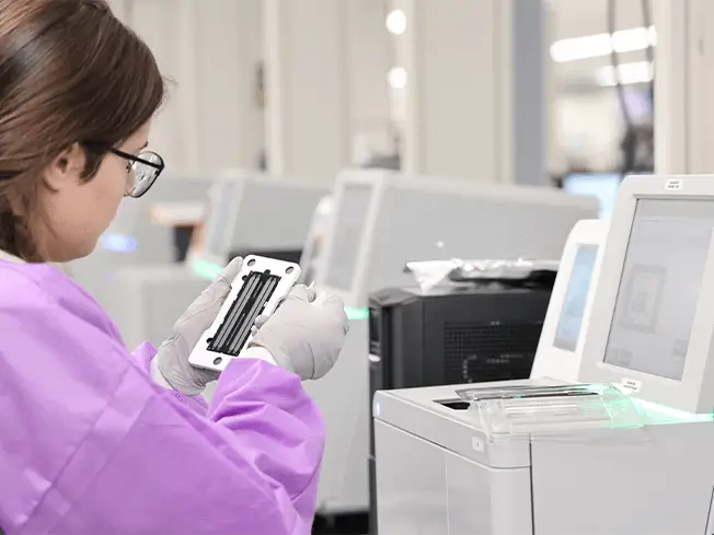 Lab technician inspects NGS oncology sample tray.